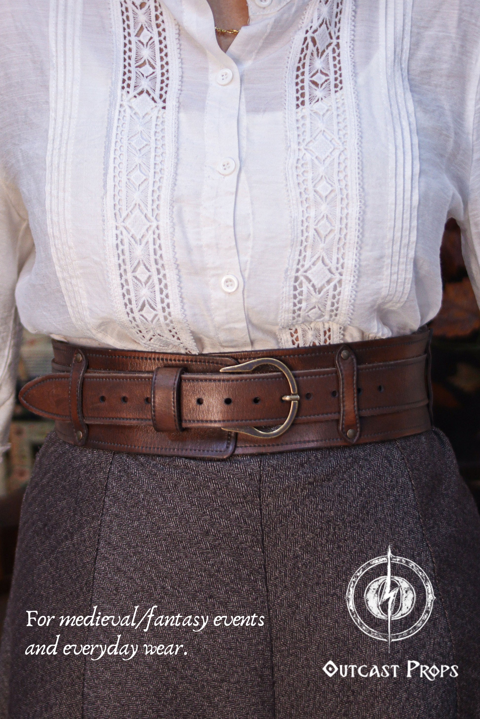 Front view of a model wearing the Handcrafted Leather Wanderer Belt in aged brown vegetable-tanned leather over high-waisted trousers and a white medieval blouse. The belt is shown with the wide outer structure and inner strap aligned, secured by a solid brass buckle. Visible stitching, burnished edges, and natural leather grain highlight artisanal craftsmanship. Modular leathePerson wearing a white blouse with lace details and a brown leather belt, with text about medieval/fantasy events and everyday wear.