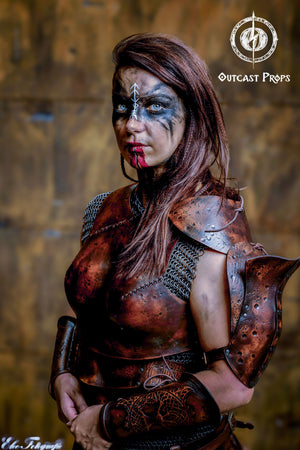Close-up of a fierce female warrior wearing distressed leather armor for LARP or cosplay. The handcrafted chestpiece and shoulder pad show battle textures and stitching. A perfect outfit for fantasy characters like rogues, scouts or barbarian women in roleplay.