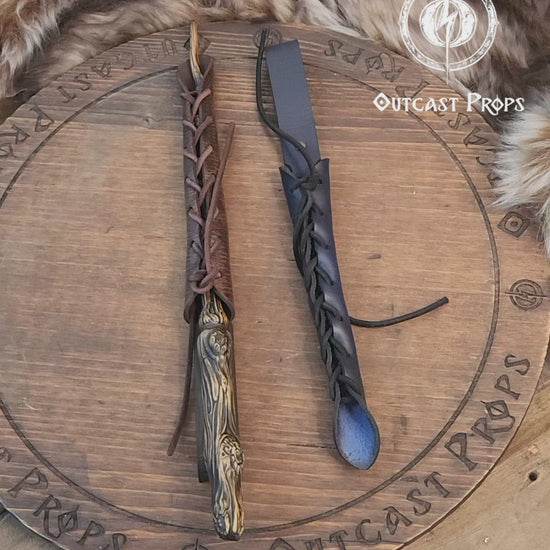 A close-up image of a brown wand holster with a leather strap and lace detail, displayed on an open book with a decorative background. Magic Wand Leather Holster Laced & Aged, perfect sheath for wizzards to hang from your belt, witch wand belt seath cosplay LARP