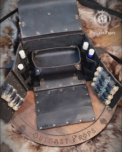 Fantasy Alchemist Bag made of natural leather, shown fully open with potion bottles, vials, and scrolls in a medieval apothecary setting. Perfect for LARP, steampunk, or cosplay characters like healers, mages, witches, or rogues. The bag includes secured compartments for bottles and a tray for tools, with quick access to emergency potions. Handmade and dyed by Outcast Props, combining practicality and immersive style for any roleplay adventure.