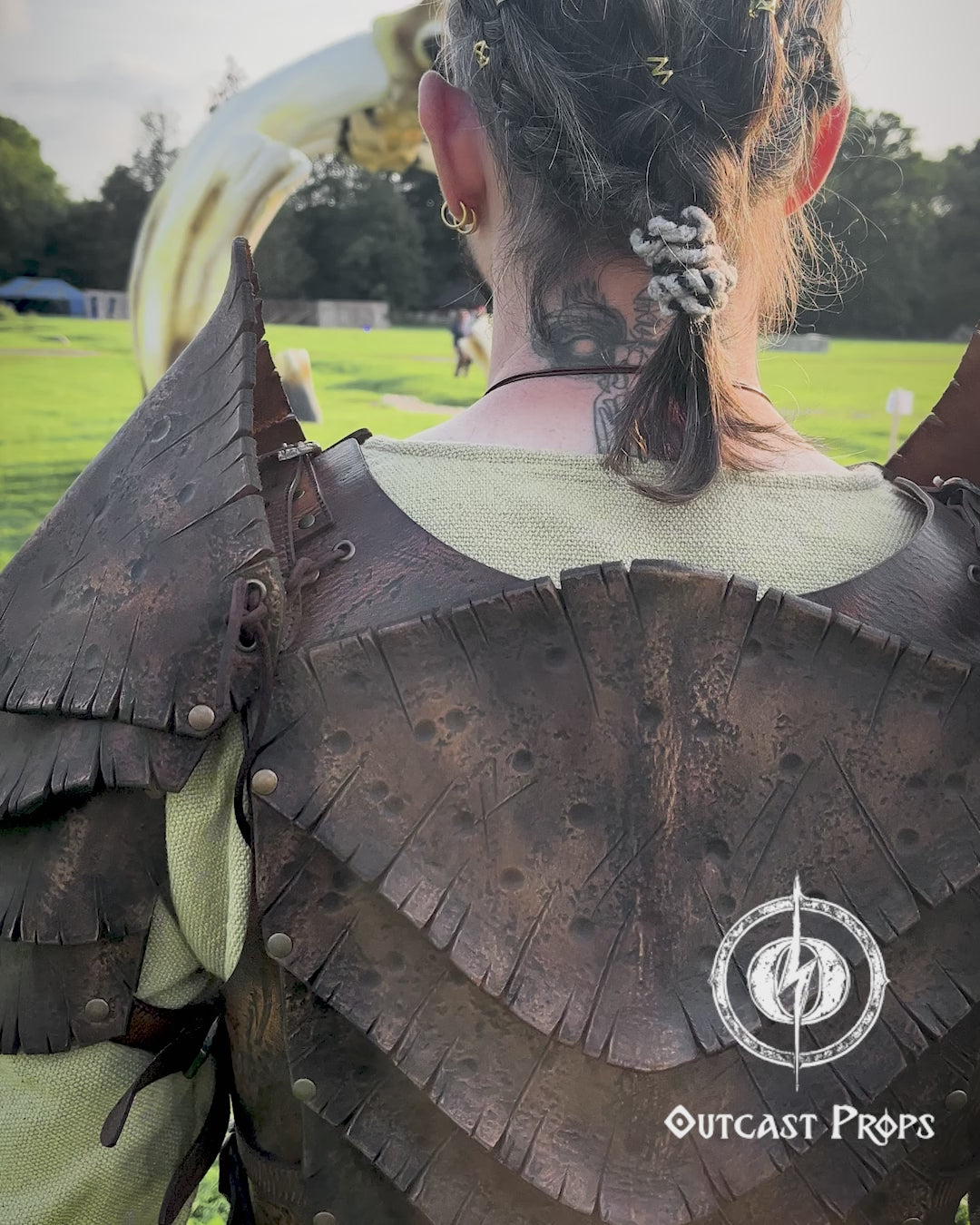 Back view of a warrior wearing the Dragon Scales Armor Set, standing before a giant bone-like sculpture at a LARP event. The armor is handmade from premium vegetable-tanned leather, textured to mimic ancient dragon hide. Shoulder guards and layered plates give a fierce, battle-ready look, ideal for cosplay, fantasy photoshoots, and immersive roleplay at Ren Faires or Viking festivals.