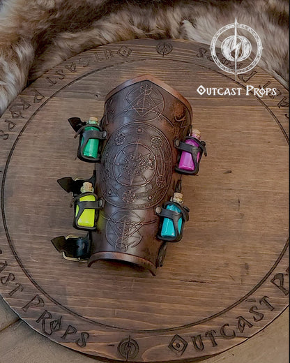 A leather bracer with metal rivets and straps, featuring intricate alchemical circles and small glass vials for storing liquids. Alchemist leather bracer with transmutation circle larp armor Wizards sorcerers and masters of the occult and the arcane