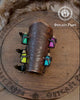 A leather bracer with metal rivets and straps, featuring intricate alchemical circles and small glass vials for storing liquids. Alchemist leather bracer with transmutation circle larp armor Wizards sorcerers and masters of the occult and the arcane