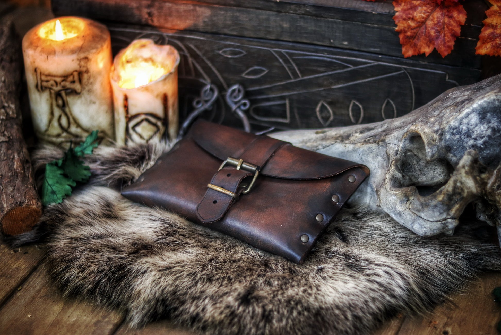 Medium brown fantasy leather belt pouch with antique brass buckle on circular wooden board engraved with Outcast Props branding. Surrounded by faux fur. Ideal for medieval scribes or LARP characters. Handcrafted pouch shows natural grain and is compatible with belts. Descriptive alt text with focus on material, use and historical style.