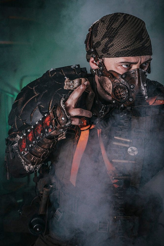 A person wearing post-apocalyptic bracers made of steel, leather, and fabric, with a gas mask and holding a rifle. Dystopian Leather & Steel Bracer: Post-Apocalyptic Arm Guard for Wasteland Cosplay and LARP