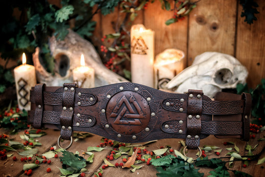 Close-up of the belt's black leather variant with worn texture and engraved knotwork. Highlighting customization options for the viking leather armor belt. Ideal for barbarian cosplay outfit, renfaire costume wide, celtic fantasy belt for LARP. Central Valknut piece and rings for attachments visible. High-contrast finish for dramatic impact.