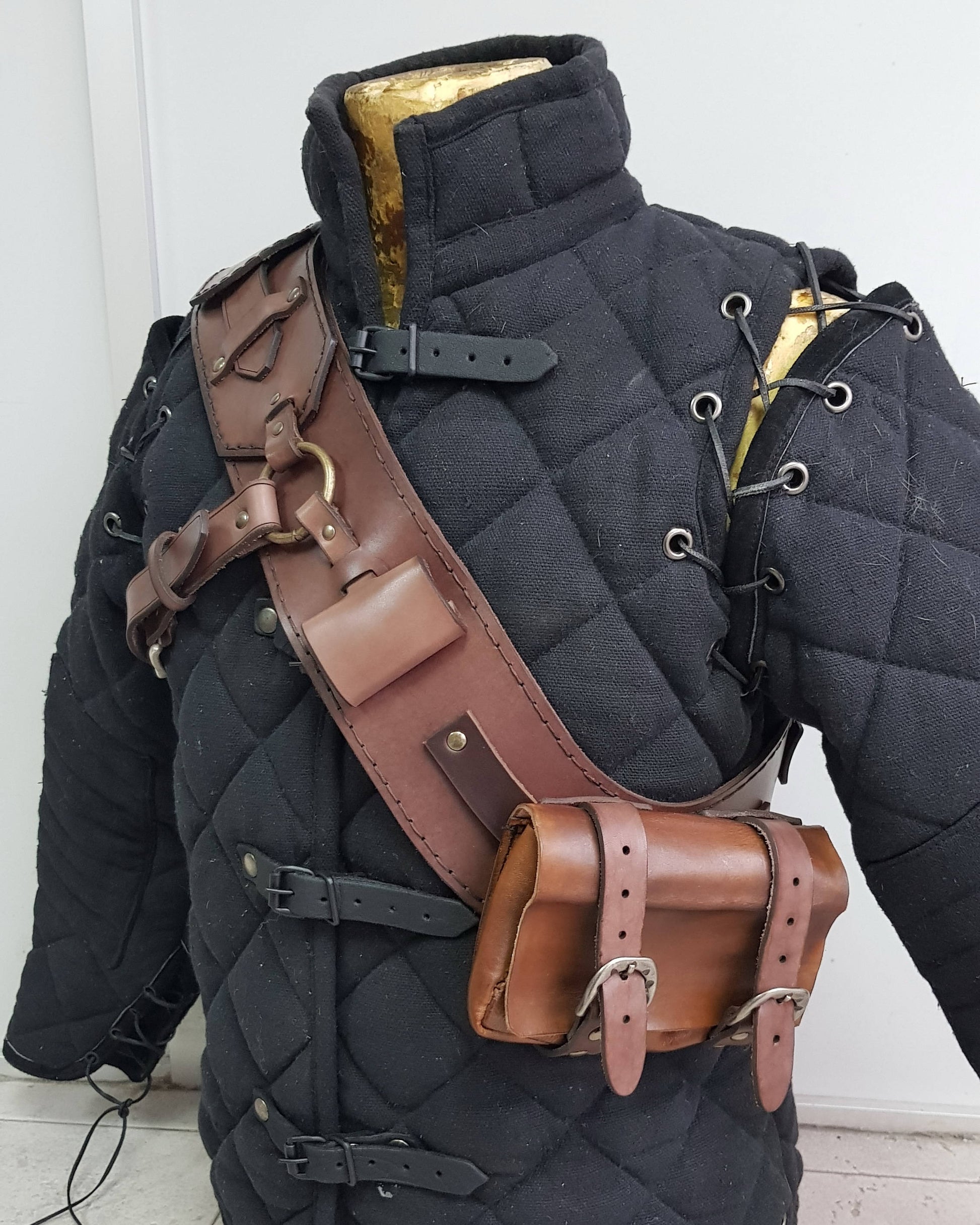 Witcher 3 ursine leather baldric shown on padded gambeson from side angle. Featuring adjustable straps, metal ring, pouches, and robust stitching. Perfect for Witcher armor cosplay, Geralt costume, LARP gear, leather baldric builds and medieval bandolier accessories.